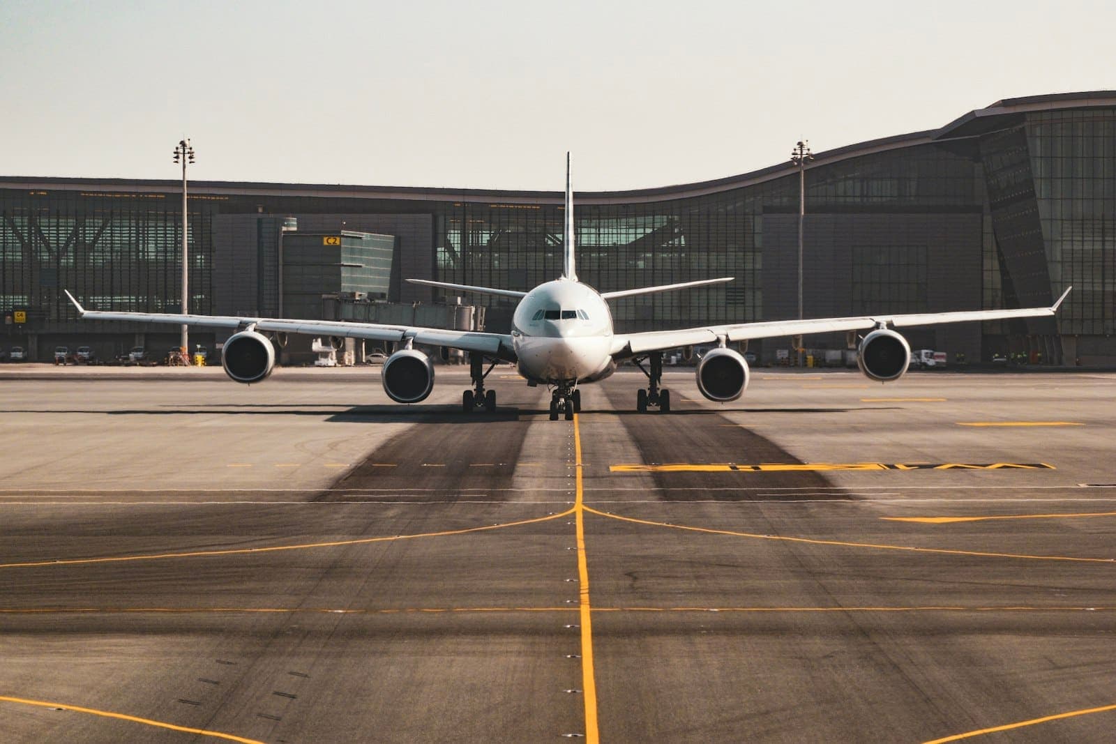 Widebody jet taxiing along the taxiway centerline toward the runway, terminal behind it